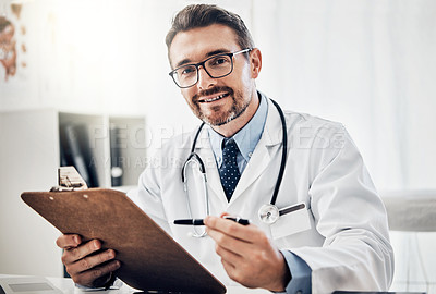 Buy stock photo Portrait of a happy doctor holding a clipboard while sitting at his desk