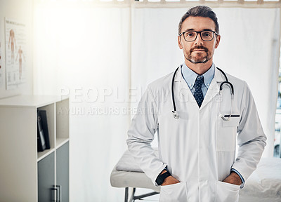Buy stock photo Portrait of a confident doctor posing with his hands in his pockets in his consultation room
