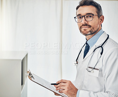 Buy stock photo Portrait of a focussed doctor reading a patient file while standing in his consultation room