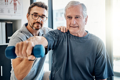 Buy stock photo Shot of a friendly physiotherapist helping his mature patient to use dumbbells in a rehabilitation center