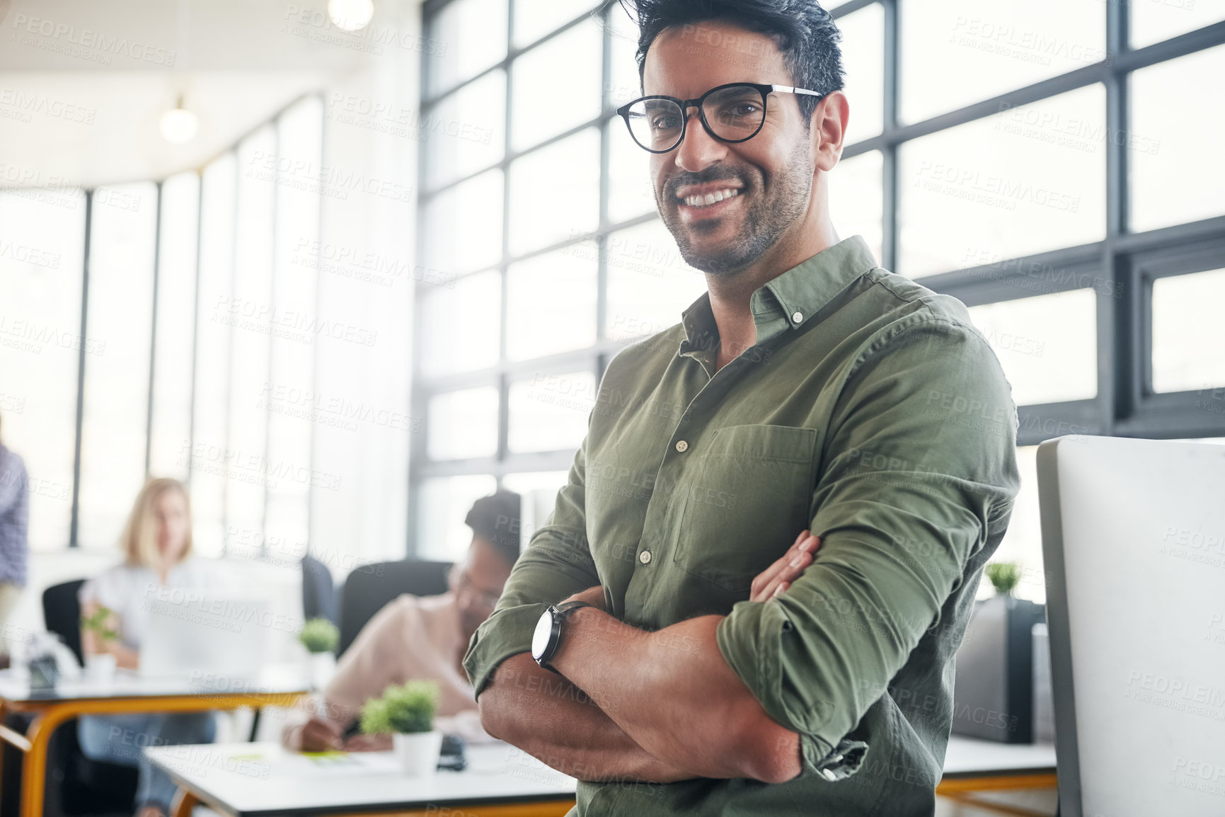 Buy stock photo Shot of a male designer in a office with his colleagues in the background