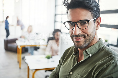 Buy stock photo Shot of a male designer in a office with his colleagues in the background