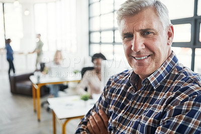 Buy stock photo Shot of a male designer in a office with his colleagues in the background