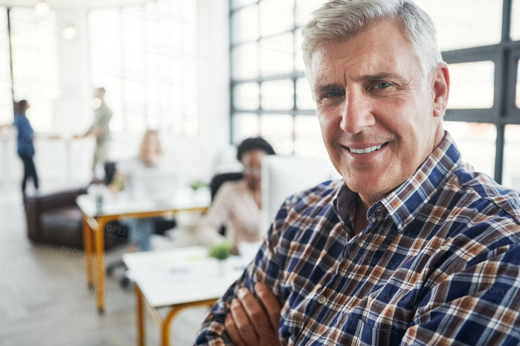 Buy stock photo Shot of a male designer in a office with his colleagues in the background