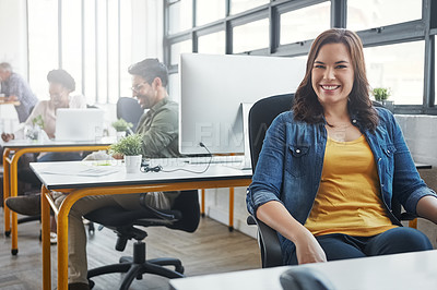 Buy stock photo Shot of a young designer in an office with her colleagues in the background