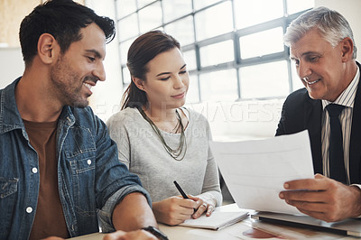 Buy stock photo Shot of a young married couple consulting with their financial advisor in his office