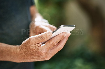 Buy stock photo Closeup shot of a senior man texting on a cellphone outside