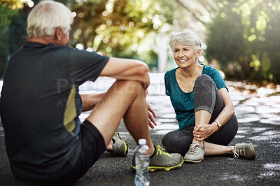 Buy stock photo Shot of a senior couple taking a break while out for a run together