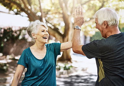 Buy stock photo Shot of a senior couple high fiving each other while out for a run together