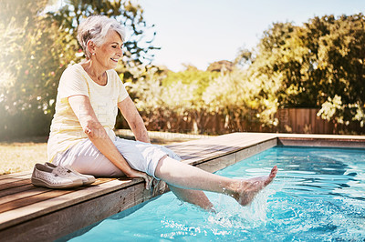 Buy stock photo Relax, travel and senior woman by the pool while on a vacation, adventure or outdoor trip in summer. Happy, smile and elderly lady in retirement with her feet in the swimming pool at a holiday resort