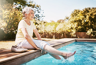 Buy stock photo Shot of a happy senior woman dipping her feet in a swimming pool