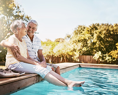 Buy stock photo Senior couple, hug and smile by swimming pool for relax, love or quality bonding time together on summer vacation. Happy elderly man holding woman relaxing with feet in water by the poolside outside