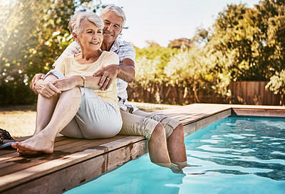 Buy stock photo Senior couple, hug and relax by pool for love and summer vacation, bonding or quality time together in the outdoors. Happy elderly man and woman relaxing and hugging with feet in water by a poolside