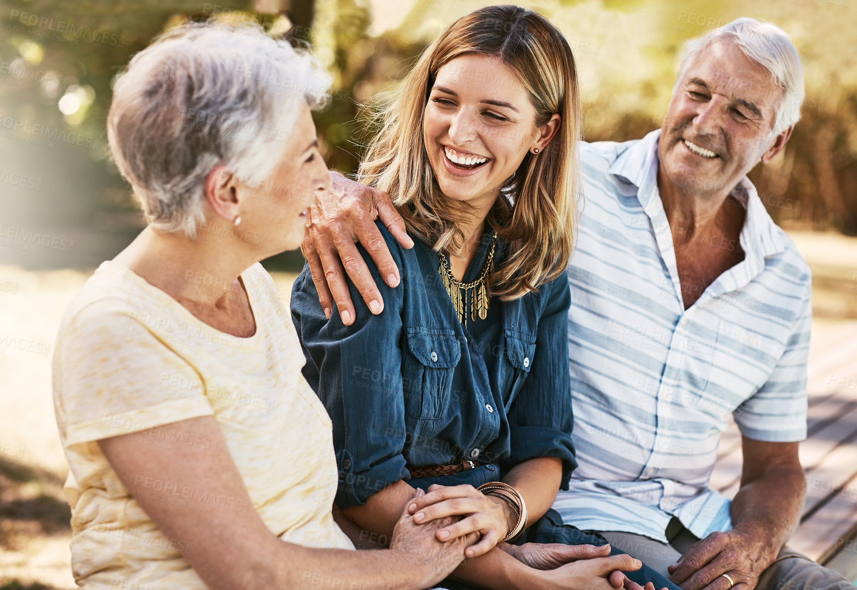 Buy stock photo Shot of a happy young woman spending quality time with her elderly parents outdoors