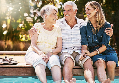 Buy stock photo Shot of a happy young woman spending quality time with her elderly parents at the pool