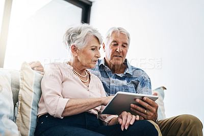 Buy stock photo Shot of a senior couple relaxing on the sofa and using a digital tablet together at home