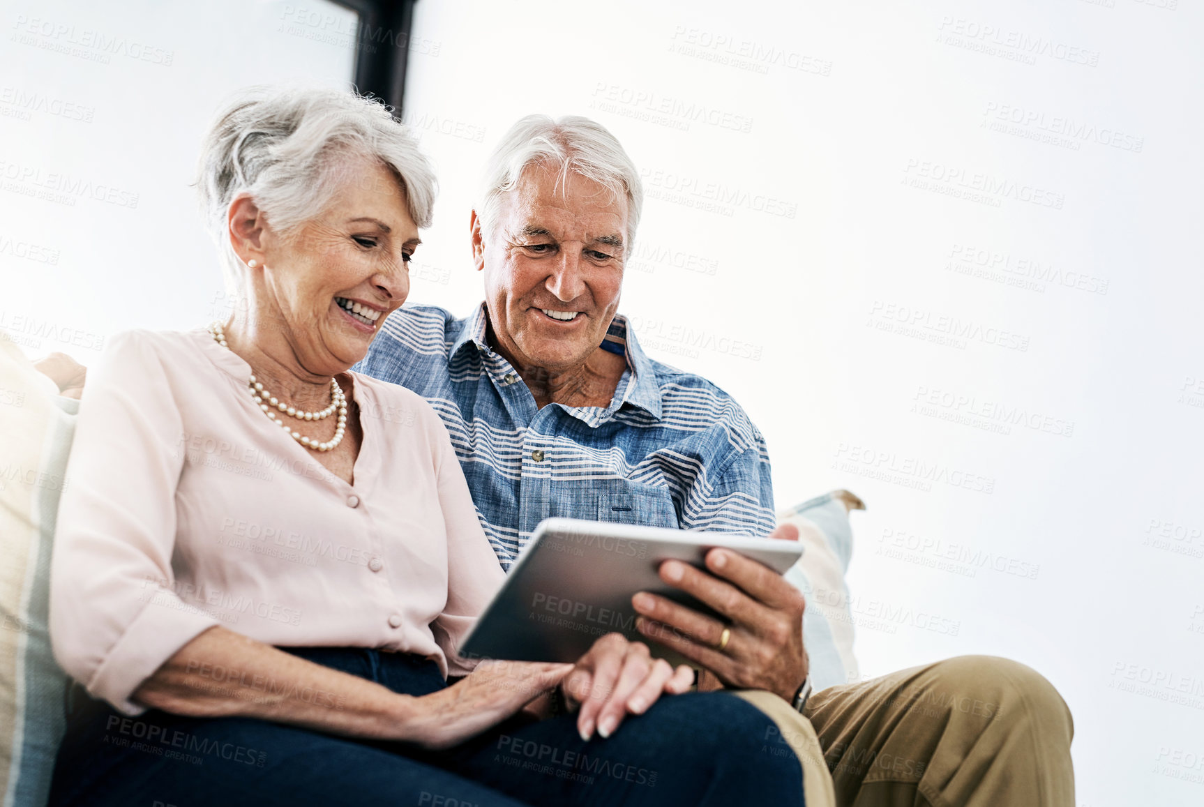 Buy stock photo Shot of a senior couple relaxing on the sofa and using a digital tablet together at home