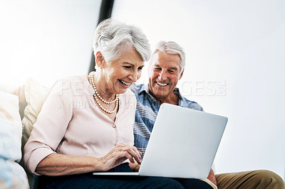 Buy stock photo Shot of a senior couple relaxing on the sofa and using a laptop together at home