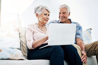 Buy stock photo Shot of a senior couple relaxing on the sofa and using a laptop together at home