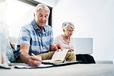 Buy stock photo Shot of a senior couple going through their paperwork together at home