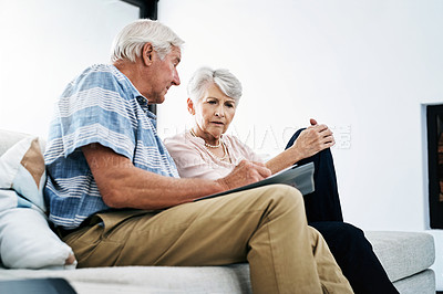 Buy stock photo Shot of a senior couple going through their finances at home and looking worried