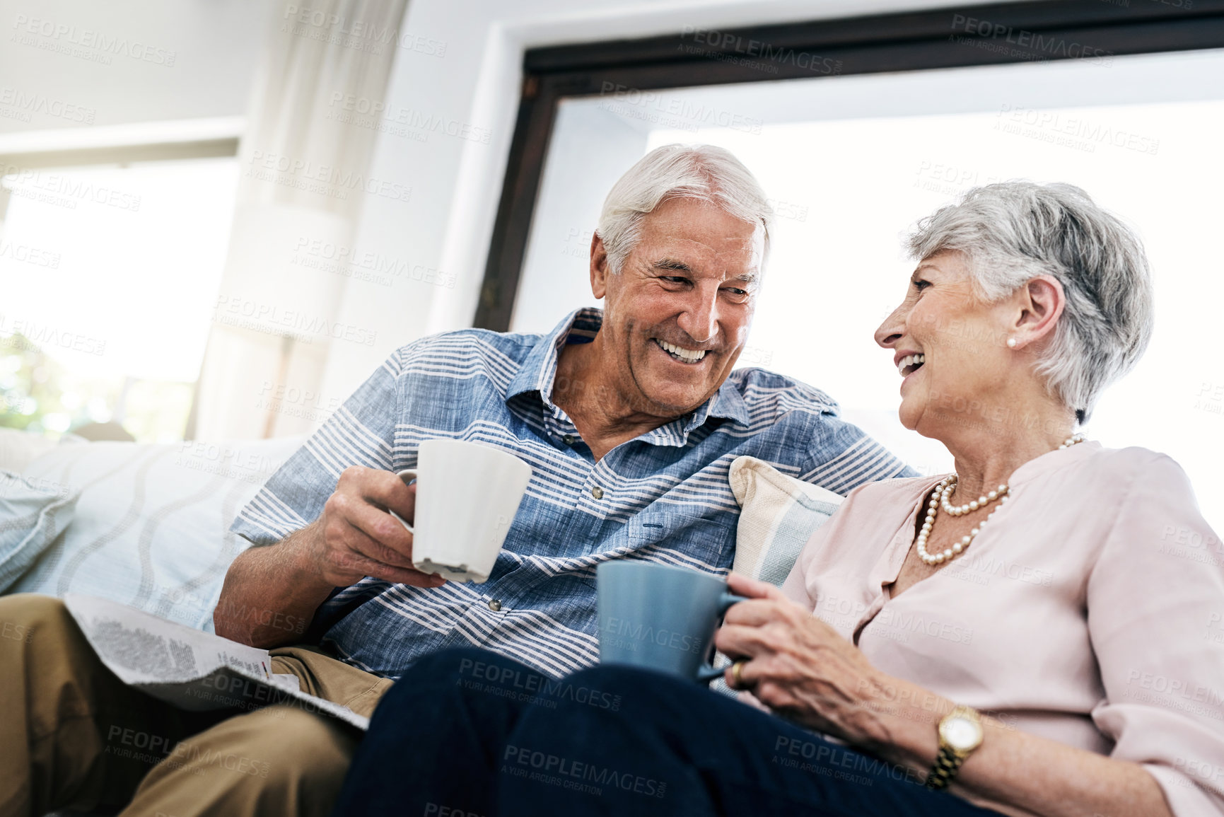 Buy stock photo Shot of a senior couple relaxing on the sofa and enjoying a coffee break at home