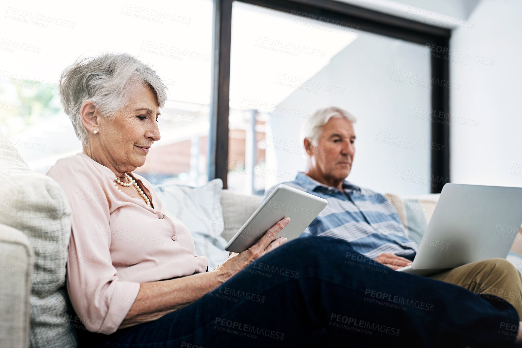 Buy stock photo Laptop, tablet and senior couple on sofa reading news on internet for political election. Relax, research and elderly man and woman on computer and digital technology to register for voting at home.