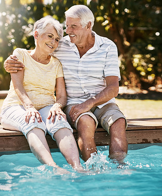 Buy stock photo Elderly couple, hug and smile by swimming pool for relax, love or quality bonding time together on summer vacation. Happy senior man holding woman relaxing with feet in water by the poolside outside