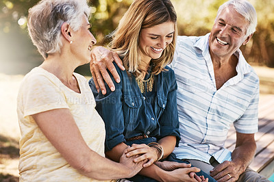 Buy stock photo Senior couple in nature with their adult daughter sitting, talking and bonding together in a garden. Happy, love and elderly people embracing child with care, happiness and affection in outdoor park.