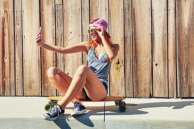 Buy stock photo Shot of a young woman taking a selfie while sitting on her skateboard