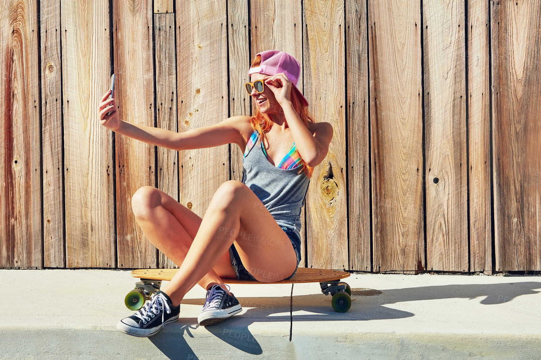 Buy stock photo Shot of a young woman taking a selfie while sitting on her skateboard