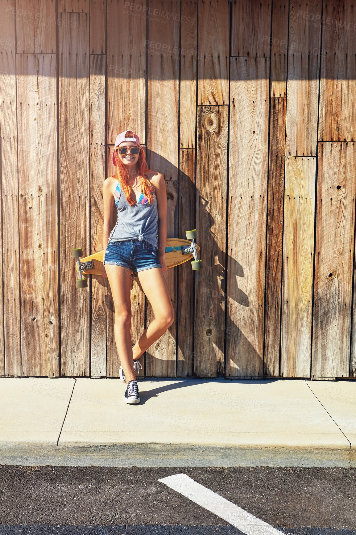 Buy stock photo Shot of a young woman hanging out on the boardwalk with her skateboard