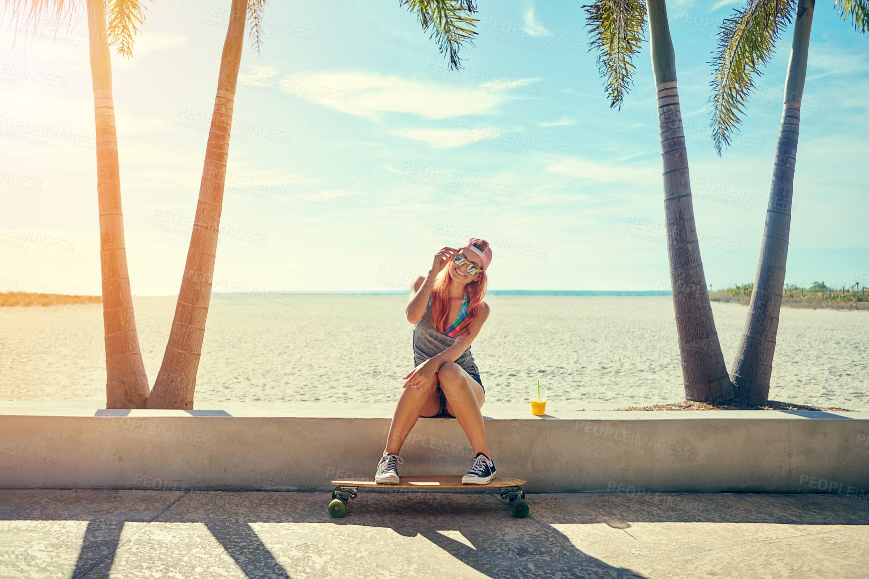 Buy stock photo Shot of a young woman hanging out on the boardwalk with her skateboard