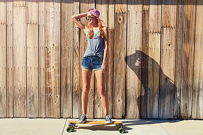 Buy stock photo Shot of a young woman hanging out on the boardwalk with her skateboard