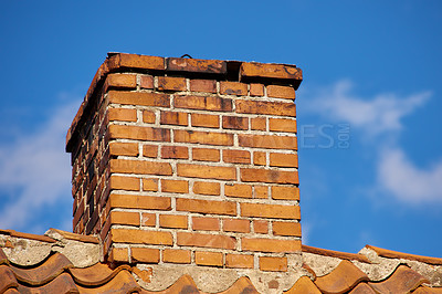 Buy stock photo Copy space with a chimney on the rooftop of a house or building against a blue sky background. Brick construction of an exterior escape chute for ventilation of air and smoke from a fireplace or oven