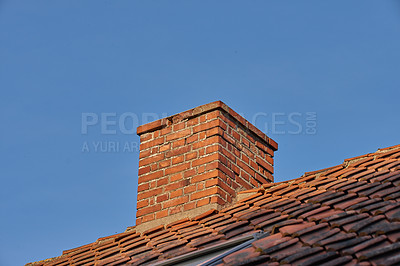 Buy stock photo Copy space with a chimney on the rooftop of a house or building against a blue sky background. Brick construction of an exterior escape chute for ventilation of air and smoke from a fireplace or oven