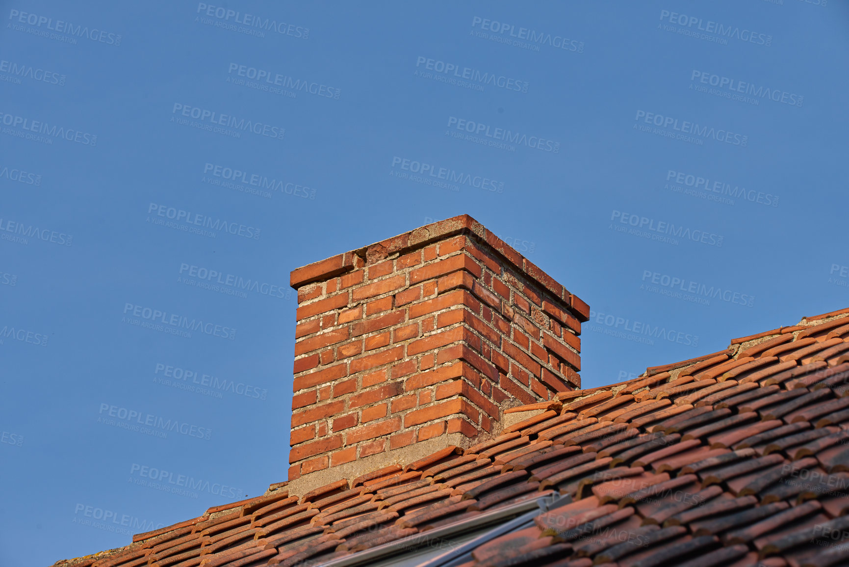 Buy stock photo Copy space with a chimney on the rooftop of a house or building against a blue sky background. Brick construction of an exterior escape chute for ventilation of air and smoke from a fireplace or oven