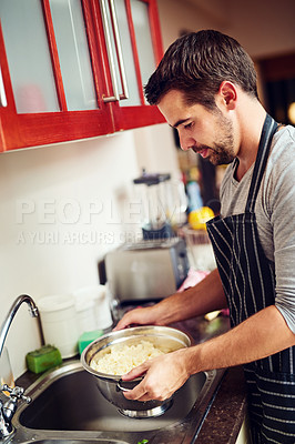 Buy stock photo Shot of a young man rinsing pasta at home