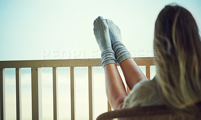 Buy stock photo Rearview shot of a woman relaxing with her feet up on the balcony