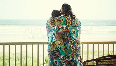 Buy stock photo Shot of an affectionate young couple wrapped in a blanket on the balcony