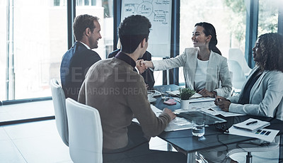 Buy stock photo Shot of two corporate colleagues shaking hands during a meeting in the boardroom