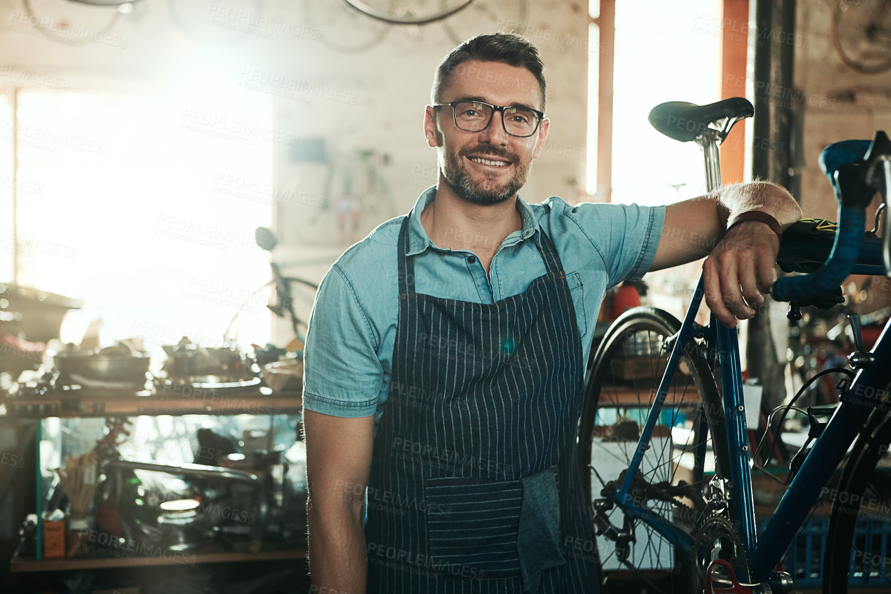 Buy stock photo Portrait, smile and man with bike for technician career, small business and entrepreneur in maintenance garage. Mature guy, bicycle mechanic and professional skills for repair in service workshop