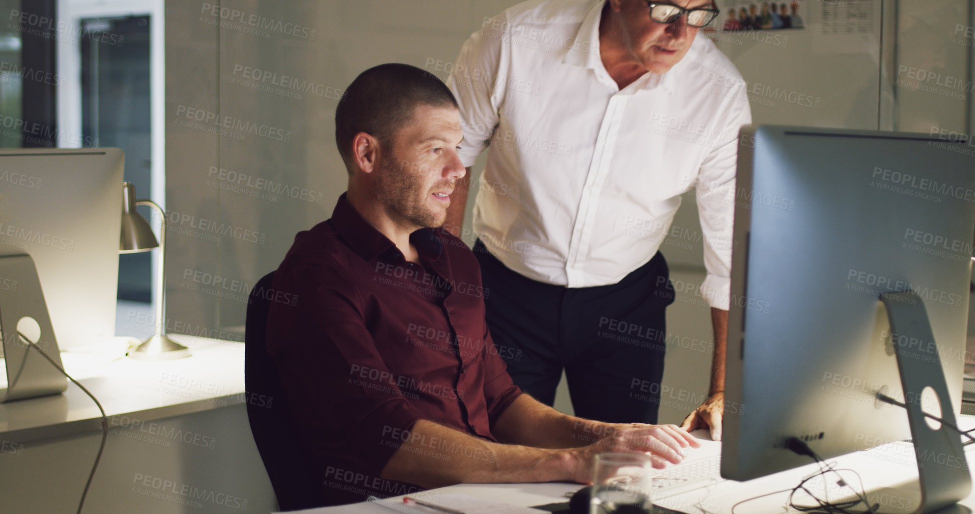 Buy stock photo Cropped shot of two businessmen working together on a computer in their office