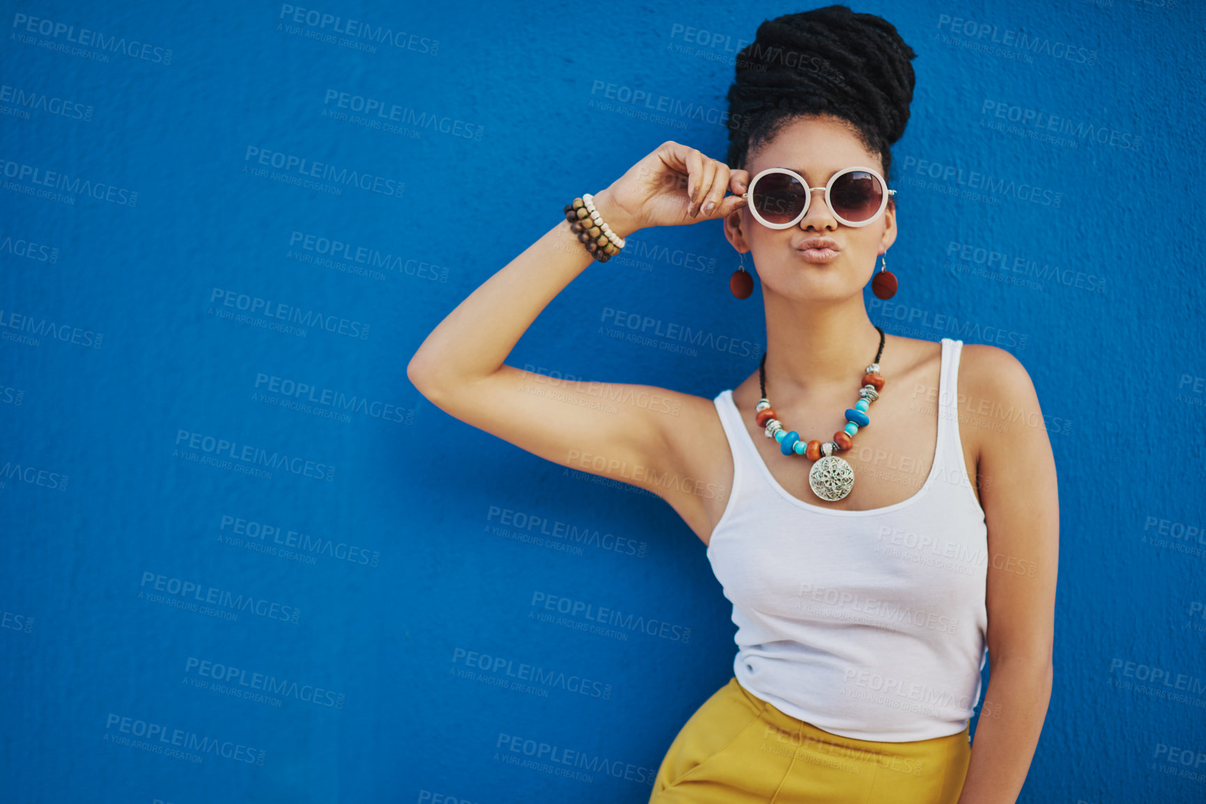 Buy stock photo Shot of an attractive young woman wearing funky sunglasses against a blue background