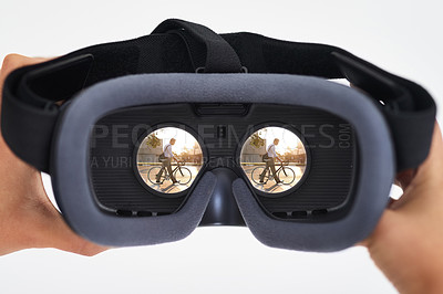 Buy stock photo Shot of a person holding a VR headset with a man riding a bicycle seen in the lenses