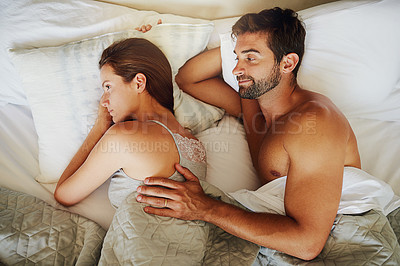 Buy stock photo Shot of a young woman ignoring her boyfriend as they lay in bed