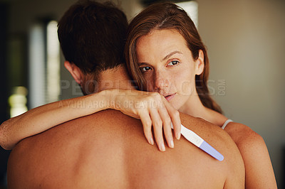 Buy stock photo Shot of a woman looking worried while hugging her boyfriend with a pregnancy test in her hand