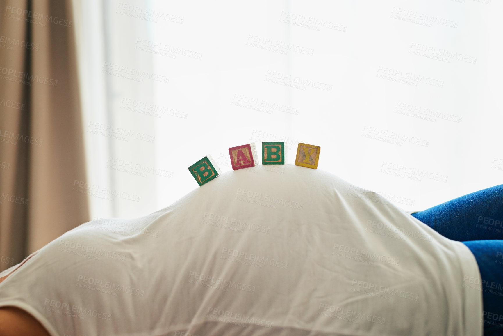 Buy stock photo Shot of an unidentifiable pregnant woman lying on her bed with blocks spelling 