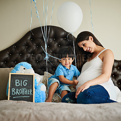 Buy stock photo Shot of a happy pregnant woman bonding with her little boy on her bed at home