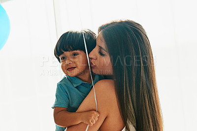 Buy stock photo Shot of a young mother cuddling her little boy while he holds a balloon at home